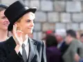 Chica tomboy con sombrero de copa y traje, haciendo un gesto con la mano.