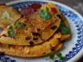 Pyszny omlet z chorizo, podany z grzankami i świeżą kolendrą, na talerzu z niebieskim wzorem.