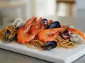 Fideuá de marisco con gambas, mejillones, almejas y pulpo sobre fideos finos.