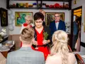 Tradycyjne błogosławieństwo pary młodej. Kobieta w czerwonej sukience trzyma gałązkę ziół, błogosławiąc narzeczonych.