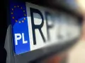 Zbliżenie na polską tablicę rejestracyjną z symbolem UE. Litery "PL" i fragment innych znaków sugerują, że pojazd jest w trakcie wyrejestrowania.
