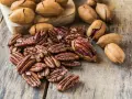 Noix de pécan décortiquées et entières sur fond de bois. Découvrez le noix de pécan bienfait pour une alimentation saine et gourmande.