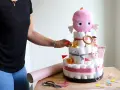 En person lägger sista handen vid en blöjtårta dekoration med en rosa bläckfisk som topp.