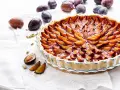 Une délicieuse tarte aux prunes, garnie de fruits frais et dorés, prête à être dégustée.