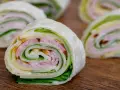 Szybkie przekąski z tortilli na zimno: zawinięte placki z szynką, serem i sałatą. Idealne na lunch lub imprezę.