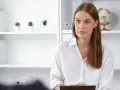 Psycholog z notatkami, w białej koszuli, siedzi naprzeciwko pacjenta. Czy do psychiatry potrzebne jest skierowanie?