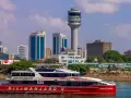 Prom na Zanzibar, "Kilimanjaro V", płynie przy nowoczesnej panoramie Dar es Salaam Tanzania, z charakterystyczną wieżą kontroli lotów.
