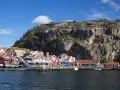 Urokliwy szwedzki port z czerwonymi domkami i skalistym wzgórzem. Czy Szwecja jest bezpieczna? Tak, wygląda na spokojne miejsce.