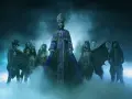 Le **chanteur** du groupe Ghost, vêtu d'une soutane violette, est entouré de musiciens masqués en squelettes, dans une atmosphère brumeuse et sombre.