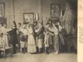 Wesele w Bronowicach. Ludzie w tradycyjnych strojach tańczą w izbie, w tle obrazy i słomiana postać.
