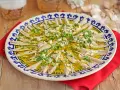 Boquerones en vinagre, un plato fresco y sabroso, servido en una fuente decorada con perejil y ajo picado.
