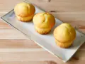 Tre soffici muffin allo yogurt dorati, pronti per essere gustati su un piatto rettangolare.