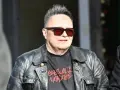 Charyzmatyczny wokalista w skórzanej kurtce i okularach przeciwsłonecznych, z charakterystyczną fryzurą.