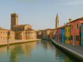 Canale di Burano con case colorate e chiese antiche, un luogo dove l'artigianato di Venezia vive ancora.