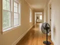 Ventilador negro en pasillo, creando una zona de ventilación. Ventanas a la izquierda, puertas a la derecha.