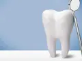 Biały ząb i lusterko dentystyczne. Pamiętaj, po piaskowaniu zębów nie wolno nic jeść przez godzinę.