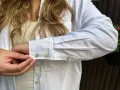 Sotto una camicia bianca, un top a coste color crema. Dettagli sui polsini con gemelli.