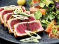 Tataki de atún perfectamente sellado, servido con una ensalada fresca de cítricos y hojas verdes.