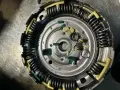 Zużyte elementy sprzęgła powershift: połamane zielone wkładki i sprężyny, objawy zużycia widoczne na metalowych częściach.