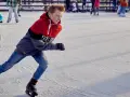 Chłopiec w kurtce i dżinsach śmiga na łyżwach po lodowisku. To jego ulubiona dyscyplina sportowa na lodzie.
