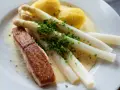 Ein Stück Lachs mit Spargel, Kartoffeln und Sauce Hollandaise. Der Spargel ist mit Schnittlauch bestreut.