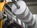 Rollo gigante de papel blanco en una máquina industrial. La densidad del papel es clave para la calidad de impresión.