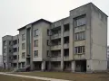 Szary blok mieszkalny z balkonami i dużymi oknami, typowy przykład architektury PRL.
