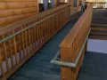 A wooden wheelchair ramp with railings curves around a log cabin. This shows how to build a wheelchair ramp for accessibility.