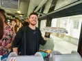 Uśmiechnięty mężczyzna z pizzą w ręku w pociągu relacji Kraków-Praga.