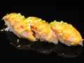 Trzy kawałki sushi z rybą i kremowym sosem, posypane szczypiorkiem. Idealne na lekki posiłek, gdy zastanawiasz się nad sushi kalorie.