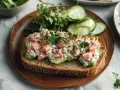 Pyszna pasta z pstrąga wędzonego na kromce chleba z ogórkiem i natką pietruszki. Idealna na szybką przekąskę.