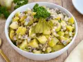 Schlesischer Kartoffelsalat mit Gurken, Zwiebeln und Petersilie, appetitlich garniert.
