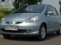 Jasnoniebieski Honda Jazz 2 na drodze, z zielenią w tle.