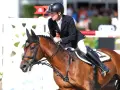 Cavalier en tenue d'équitation, sur un cheval bai, en plein saut. Le cheval, nommé Ratina Z, est concentré.
