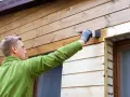 Mężczyzna maluje deskę elewacyjną, tworząc piękne aranżacje.
