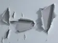 Pintura desconchada revela capas de color gris bajo la superficie blanca.