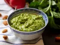 Zielone pesto z liści rzodkiewki, z migdałami i świeżymi liśćmi w tle. Idealne do makaronu lub jako dodatek do kanapek.