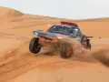 Un'auto da rally Audi sfreccia tra le dune, sollevando sabbia. Un'emozionante tappa del percorso Parigi-Dakar.