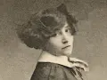 Portrait de Colette jeune, regardant par-dessus son épaule, avec une coiffure bouclée et un col blanc.