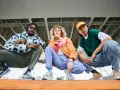 Tre giovani con look urbani, ognuno con le sue sneakers, mostrano cosa sono le sneakers: calzature comode e alla moda per ogni stile.