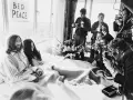 John Lennon i Yoko Ono w łóżku, otoczeni przez reporterów z aparatami. Na ścianie wisi plakat "BED PEACE".