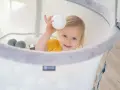 Uśmiechnięte dziecko bawi się w basenie z piłeczkami. To świetne ćwiczenia na czucie głębokie dla dzieci, rozwijające zmysły i koordynację.