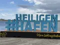 Große blaue Buchstaben mit #Heiligenhafen auf einem Holzpodest. Perfekt für Ausflugsziele und Erinnerungen an diesen schönen Ort.
