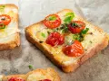 Pyszna, lekka kolacja: tosty z roztopionym serem, pieczonymi pomidorkami koktajlowymi i szczypiorkiem. Idealne na szybki posiłek.