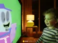 Mała dziewczynka z zaciekawieniem ogląda na ekranie telewizora krótkie filmy dla dzieci z zabawną postacią.