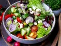 Ein bunter gemischter Salat mit Tomaten, Gurken, Radieschen, Zwiebeln und Feta.