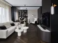 Nowoczesny salon z wygodną sofą, stolikami i regałem pełnym książek. Dominują ciemne, grafitowe akcenty, tworząc elegancką atmosferę.