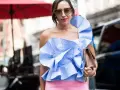 Eleganza in **abbinamento rosa e blu**: top a balze a righe azzurre e bianche con pantaloni rosa cipria, occhiali da sole e borsa a tracolla.