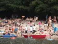 Tłum ludzi odpoczywa na plaży nad jeziorem w Jelczu Laskowicach. Słońce, piasek i woda tworzą idealne warunki do letniego relaksu.