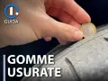 Una mano tiene una moneta da 1 euro per controllare l'usura di una gomma. Gomme lisce come capire quando cambiarle.